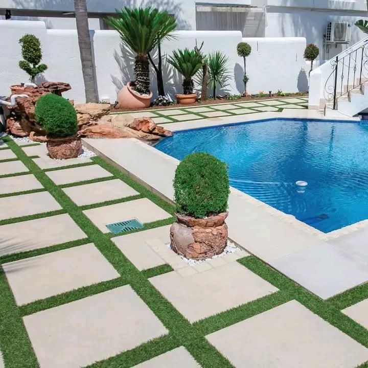 Paved pool surround with lawn and potted plants