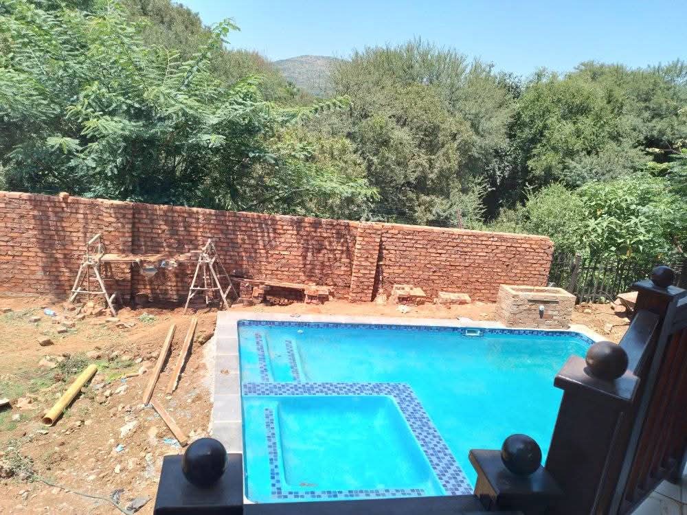 Swimming pool taking shape behind a brick wall